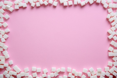 Frame of refined sugar cubes on color background, top view