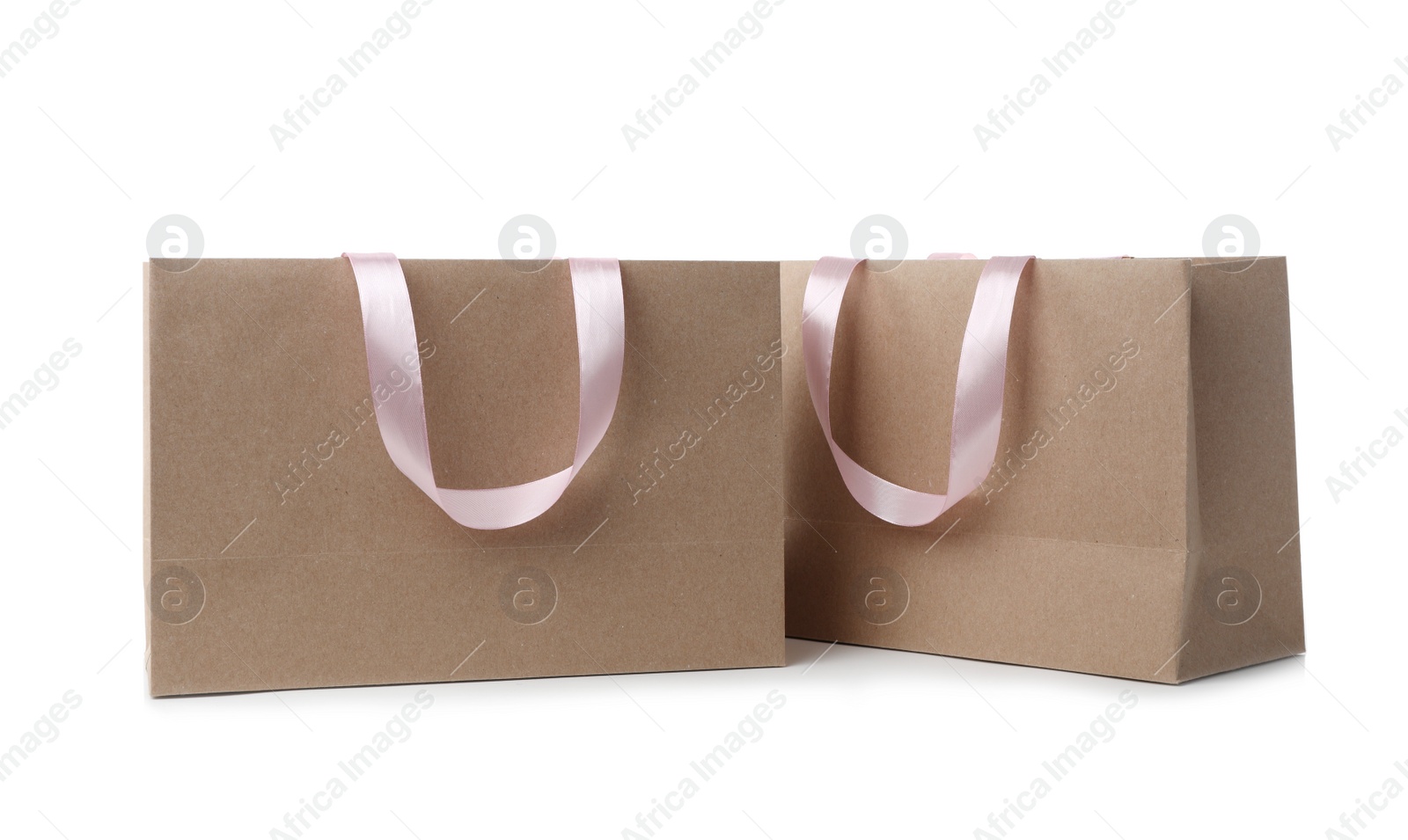 Photo of Paper shopping bags with ribbon handles on white background. Mockup for design