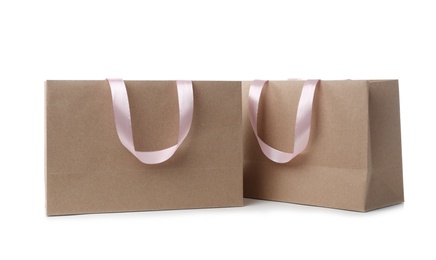 Photo of Paper shopping bags with ribbon handles on white background. Mockup for design