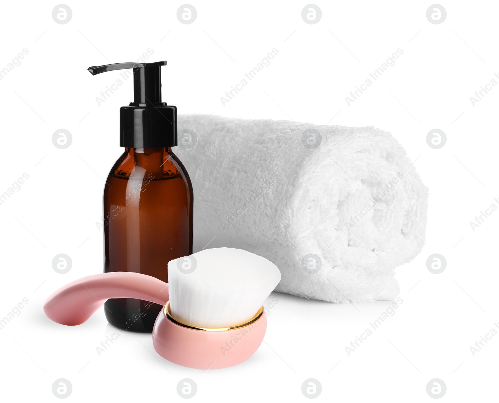 Image of Rolled clean towel, bottle of hydrophilic oil and face cleansing brush on white background