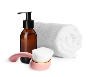 Image of Rolled clean towel, bottle of hydrophilic oil and face cleansing brush on white background