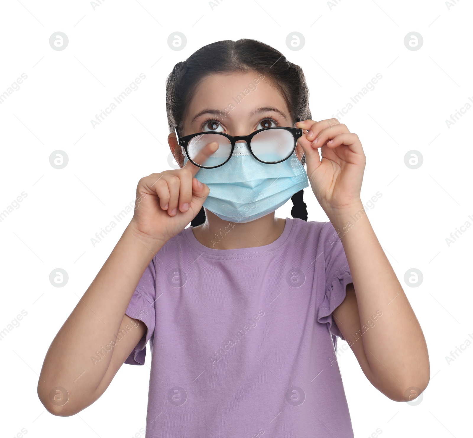 Photo of Little girl wiping foggy glasses caused by wearing medical face mask on white background. Protective measure during coronavirus pandemic