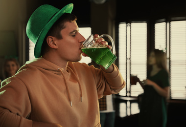 Photo of Man drinking green beer in pub. St. Patrick's Day celebration