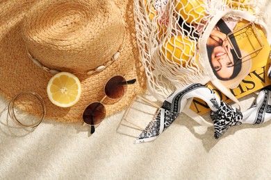 Photo of String bag with fashion magazine, fresh lemons and accessories on beige textured background, flat lay