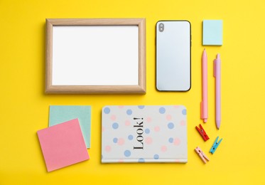 Photo of Blank white board with stationery and smartphone on yellow background, flat lay. Space for text