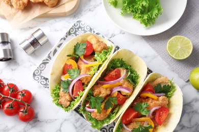 Photo of Yummy fish tacos served on white marble table, flat lay