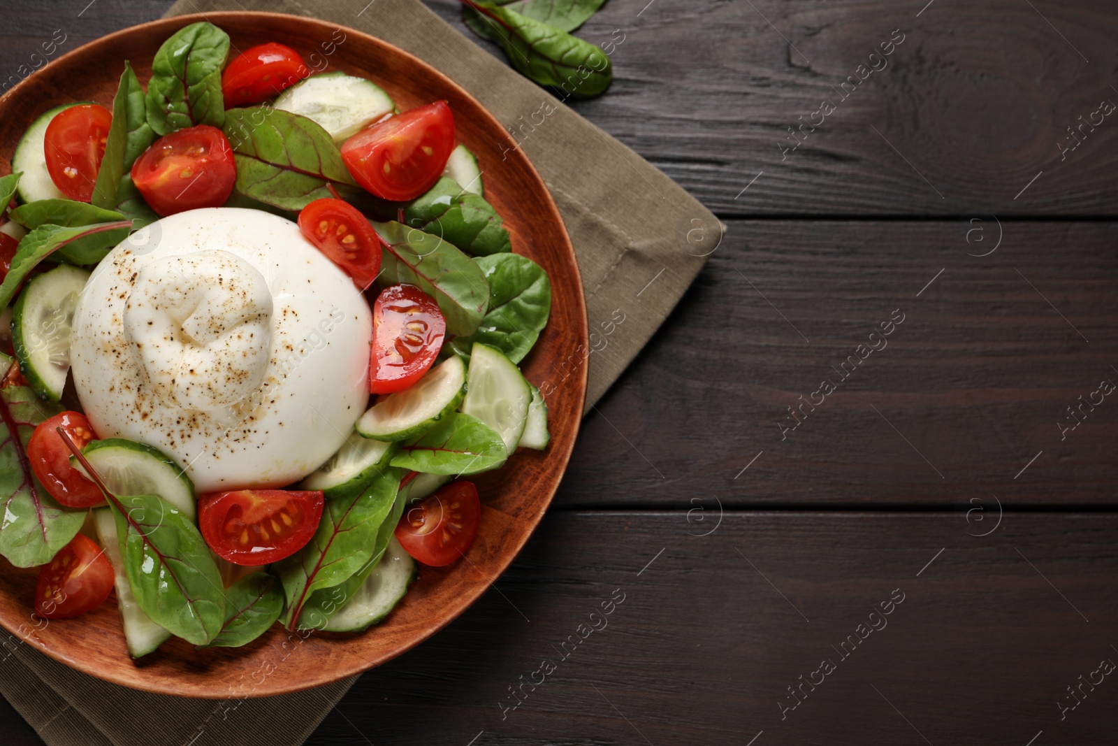 Photo of Delicious burrata salad served on wooden table, top view. Space for text