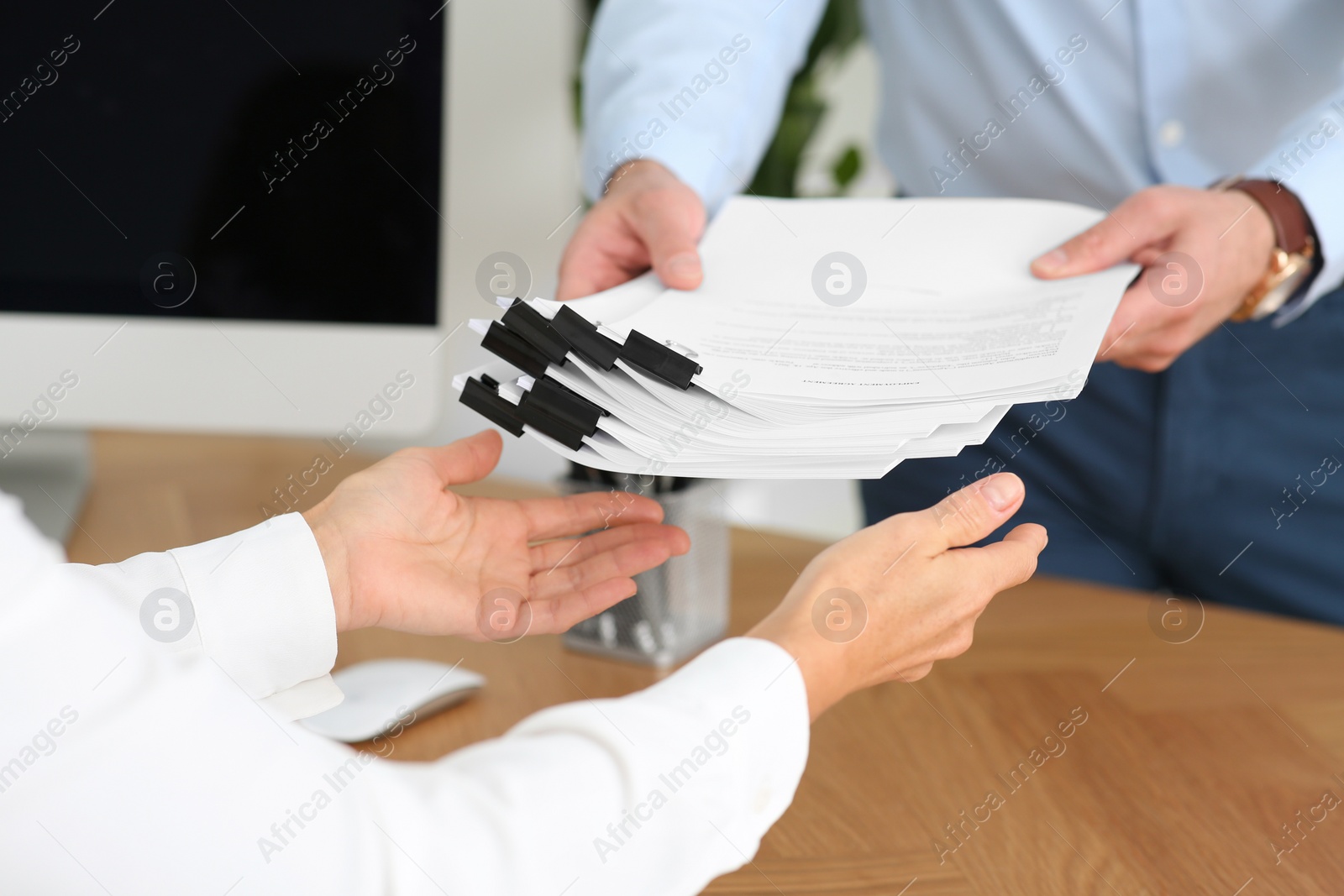 Photo of Man giving documents to colleague in office, closeup