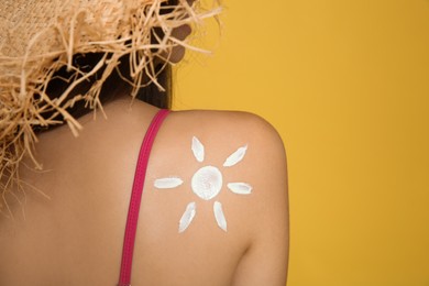 Photo of Teenage girl with sun protection cream on her back against yellow background, closeup. Space for text