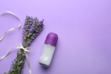 Female deodorant and lavender flowers on lilac background, flat lay. Space for text