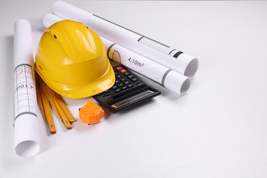 Construction drawings, safety hat, calculator, tape measure and folding ruler on white background. Space for text