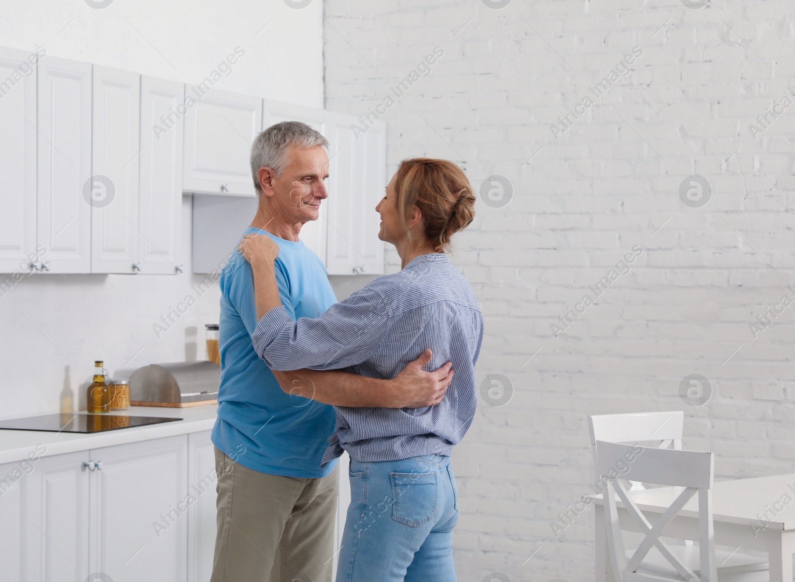 Photo of Happy senior couple dancing together in kitchen