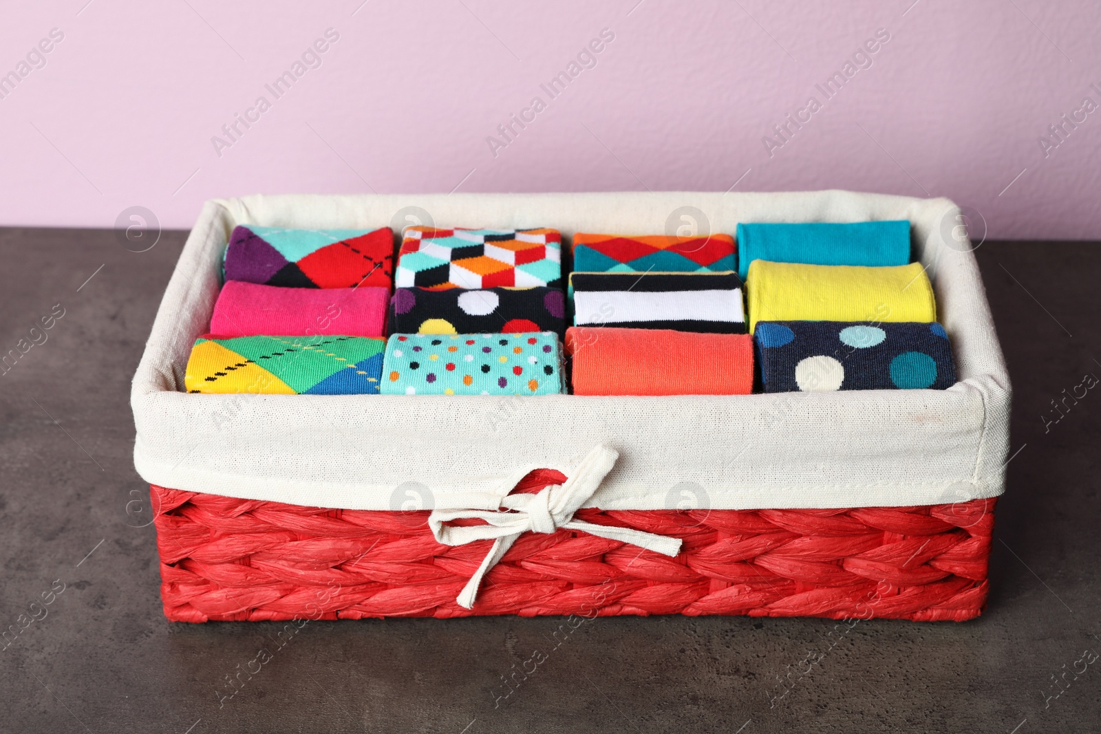 Photo of Box with colorful socks on dark table against color background