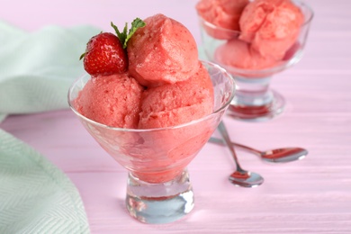 Photo of Delicious strawberry ice cream in dessert bowl on pink wooden table, closeup