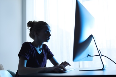 Photo of Shocked teenage girl using computer at table indoors. Danger of internet