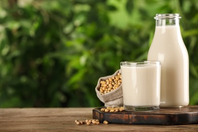 Photo of Fresh soy milk and grains on white wooden table against blurred background. Space for text