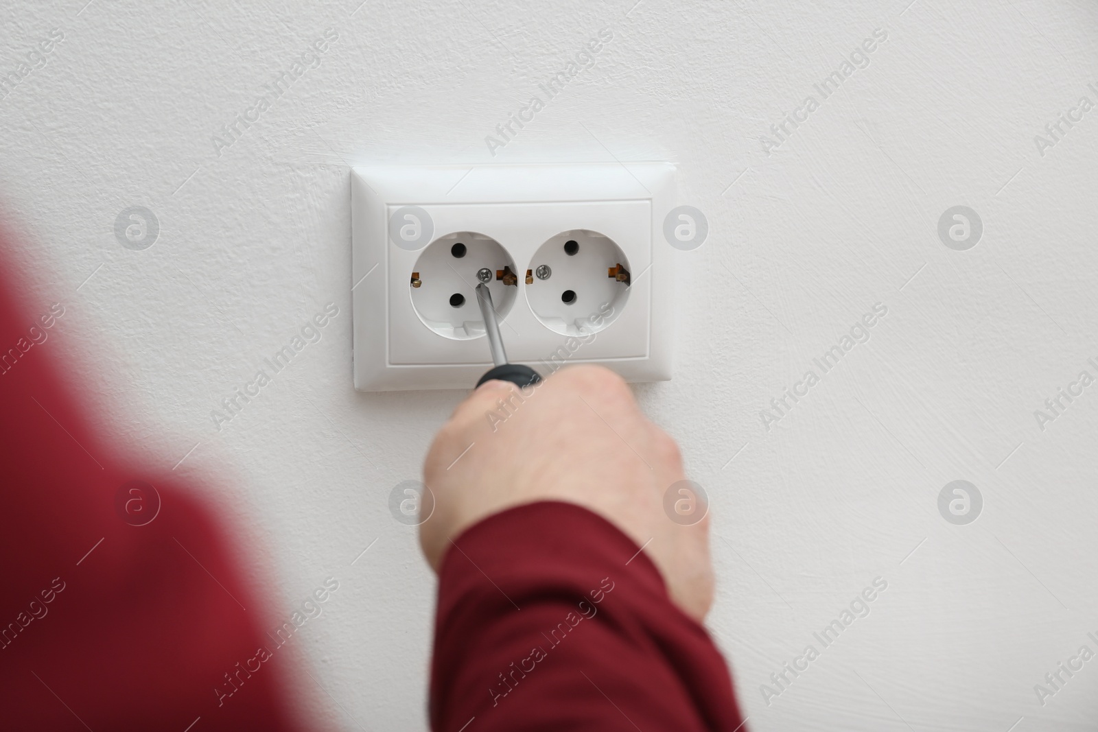 Photo of Electrician repairing wall sockets on white background, closeup