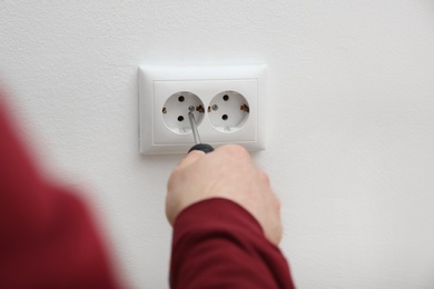 Electrician repairing wall sockets on white background, closeup