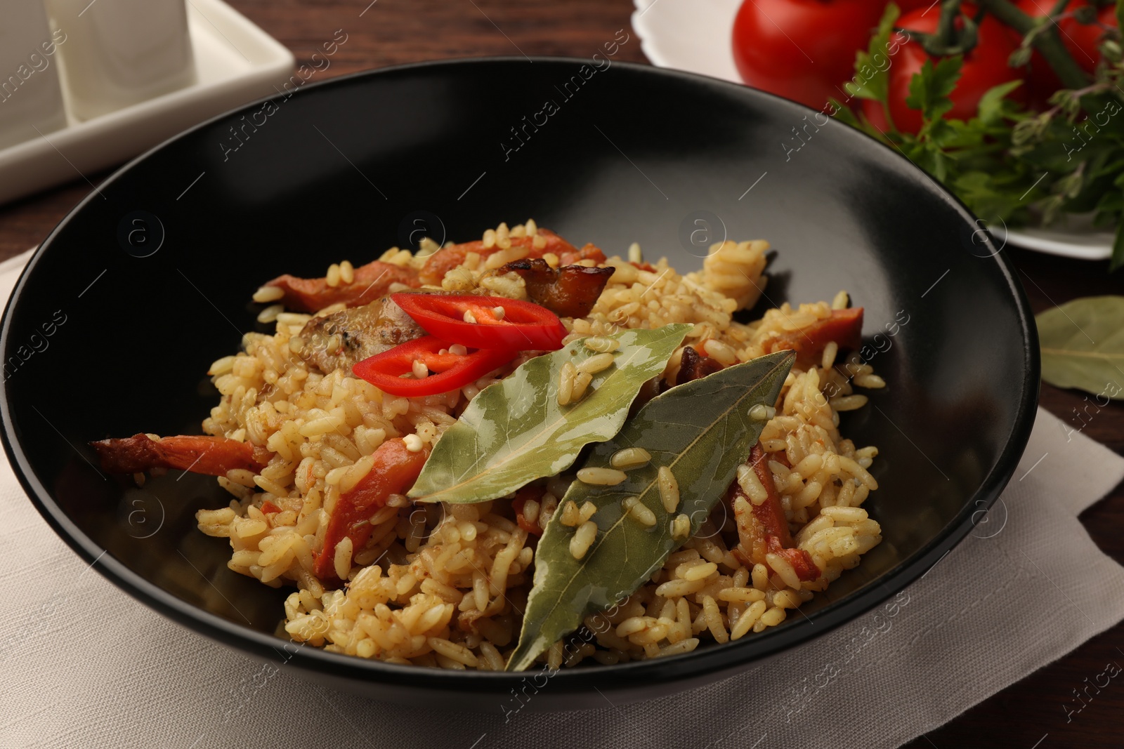 Photo of Delicious pilaf and bay leaves in bowl on table