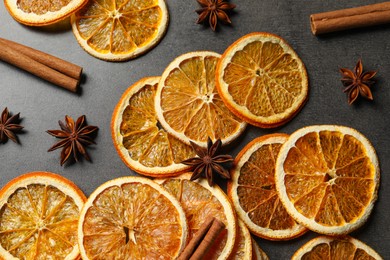 Photo of Dry orange slices, cinnamon sticks and anise stars on black table, flat lay