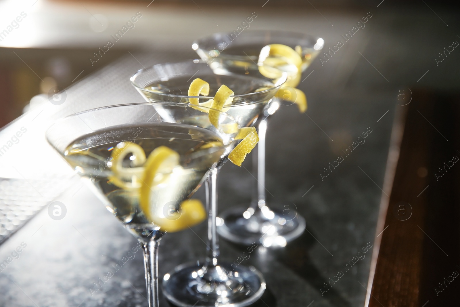 Photo of Glasses of lemon drop martini cocktail on bar counter, closeup. Space for text