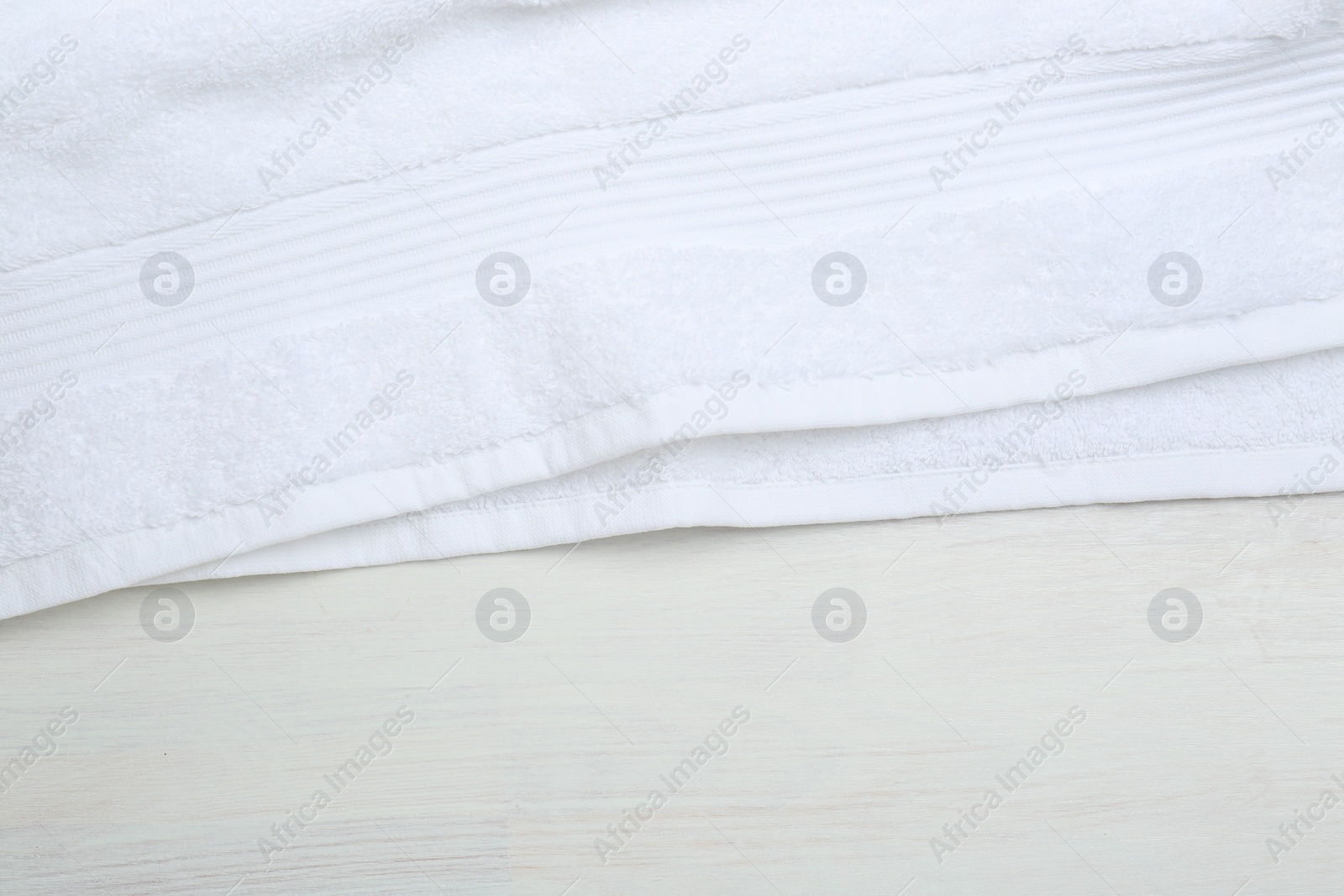 Photo of White terry towel on light wooden table, top view. Space for text