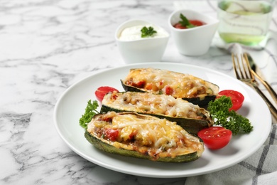 Photo of Baked stuffed zucchinis served on white marble table