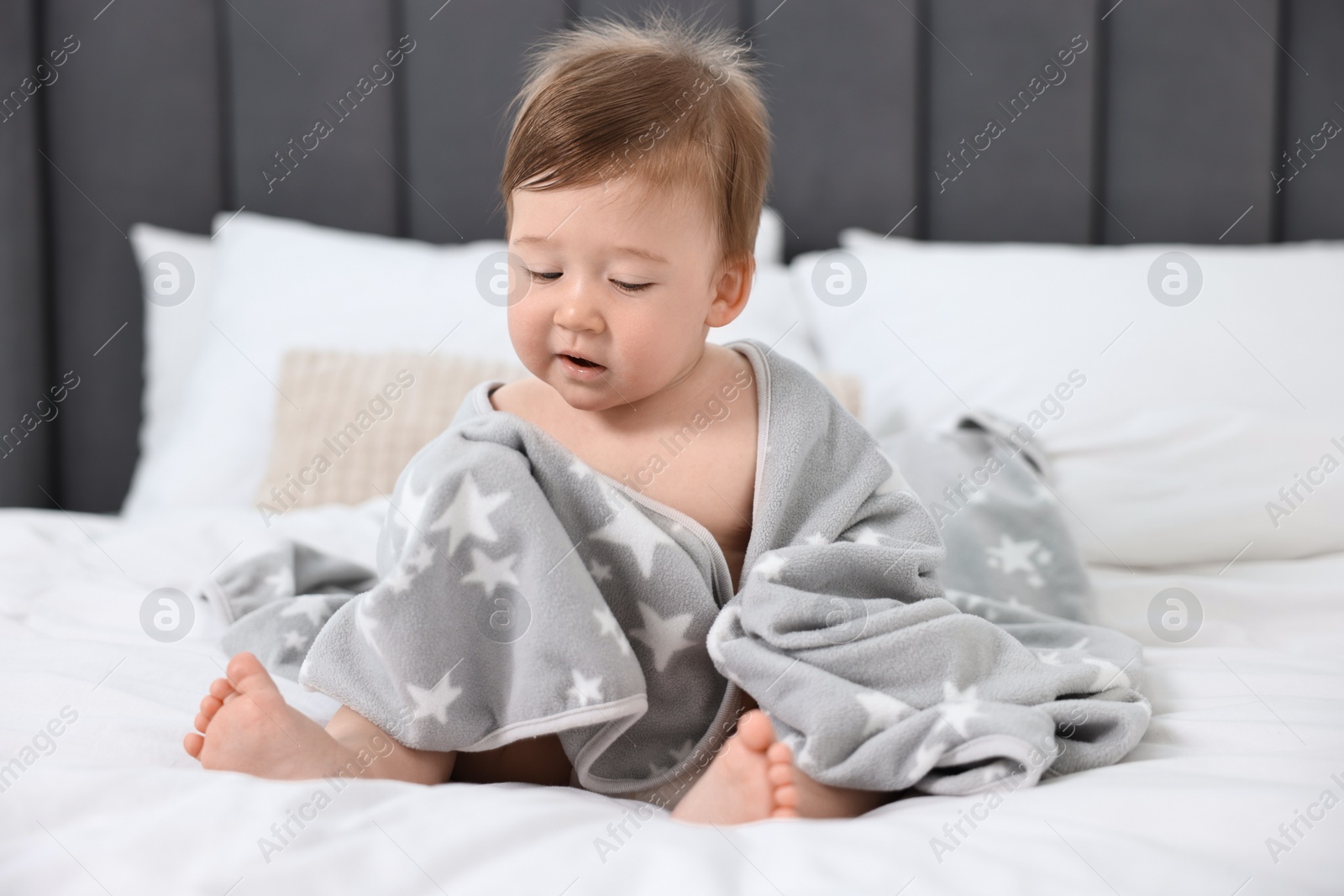 Photo of Cute baby boy with blanket sitting on bed at home