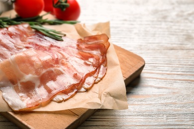 Photo of Board with raw bacon rashers on wooden background