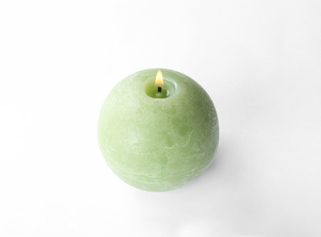 Small burning green candle isolated on white