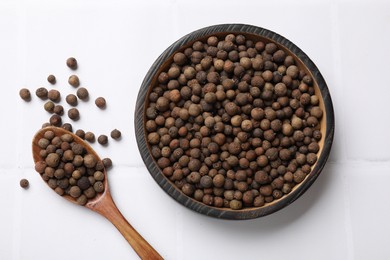 Photo of Dry allspice berries (Jamaica pepper) on white tiled table, top view