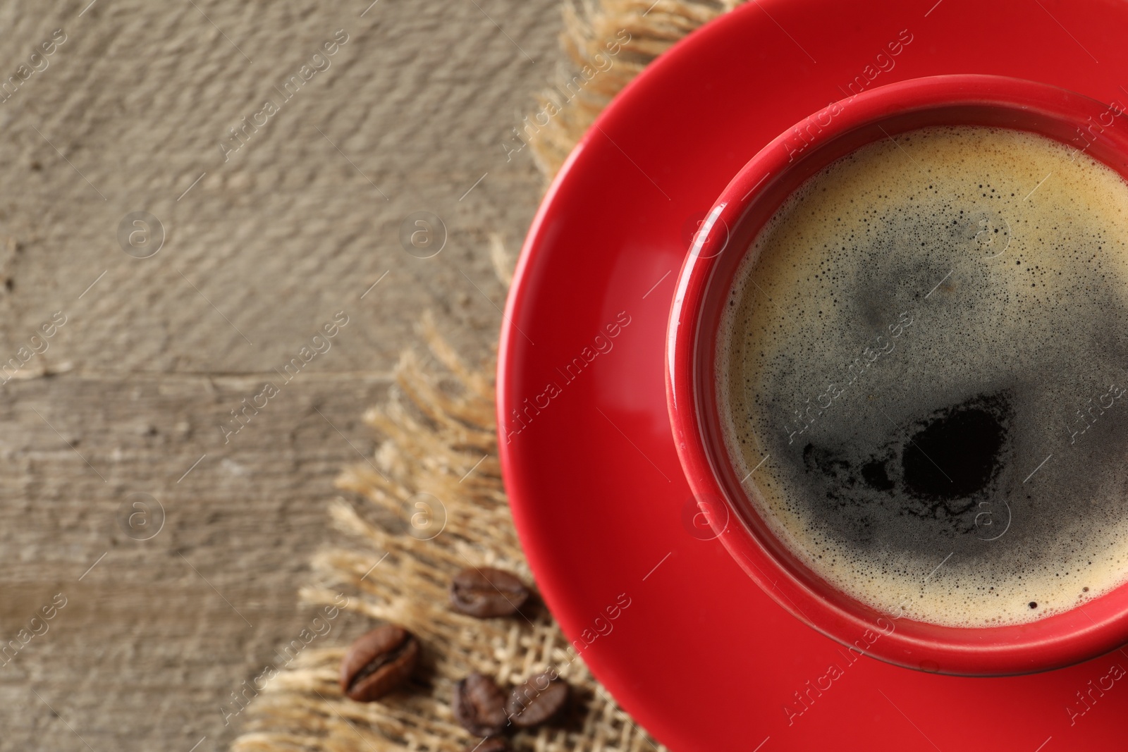 Photo of Cup of aromatic coffee on wooden table, top view. Space for text