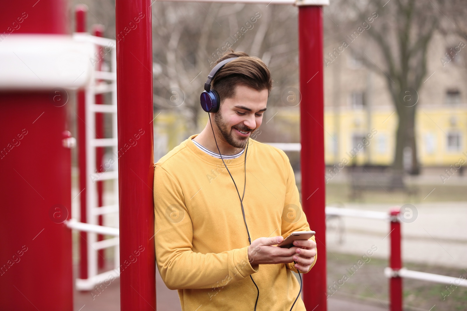 Photo of Young man with headphones listening to music on sports ground