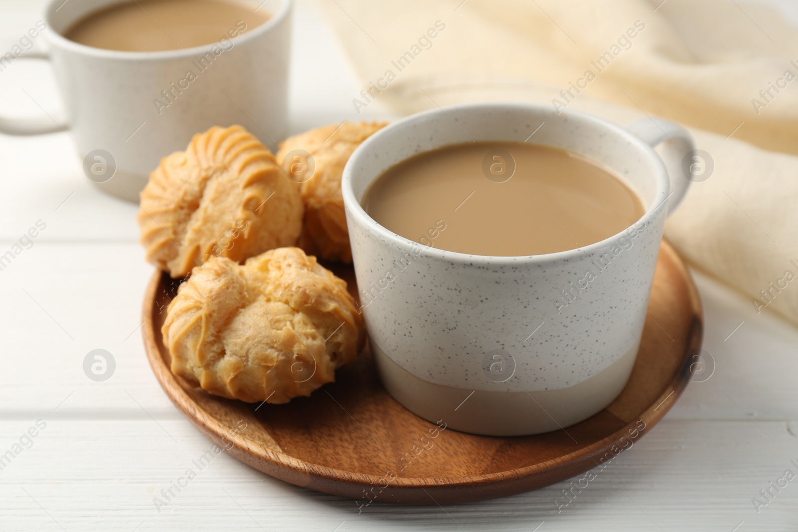 Photo of Aromatic coffee in cup and tasty profiteroles on white wooden table