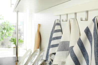 Photo of Different kitchen towels hanging on hook rack indoors, closeup