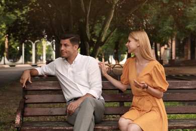 Man having boring date with talkative woman on bench at park