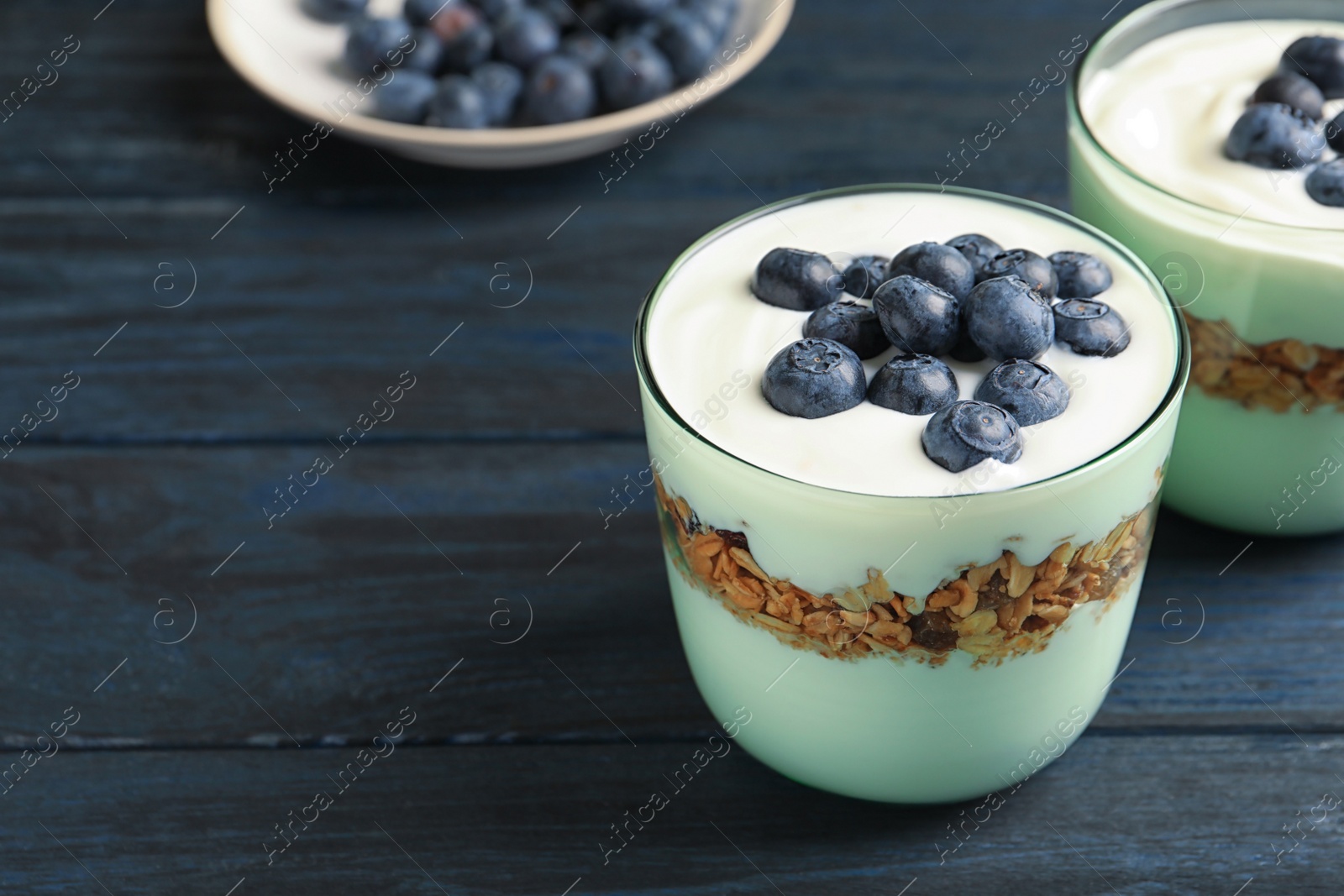 Photo of Glass with yogurt, berries and granola on table