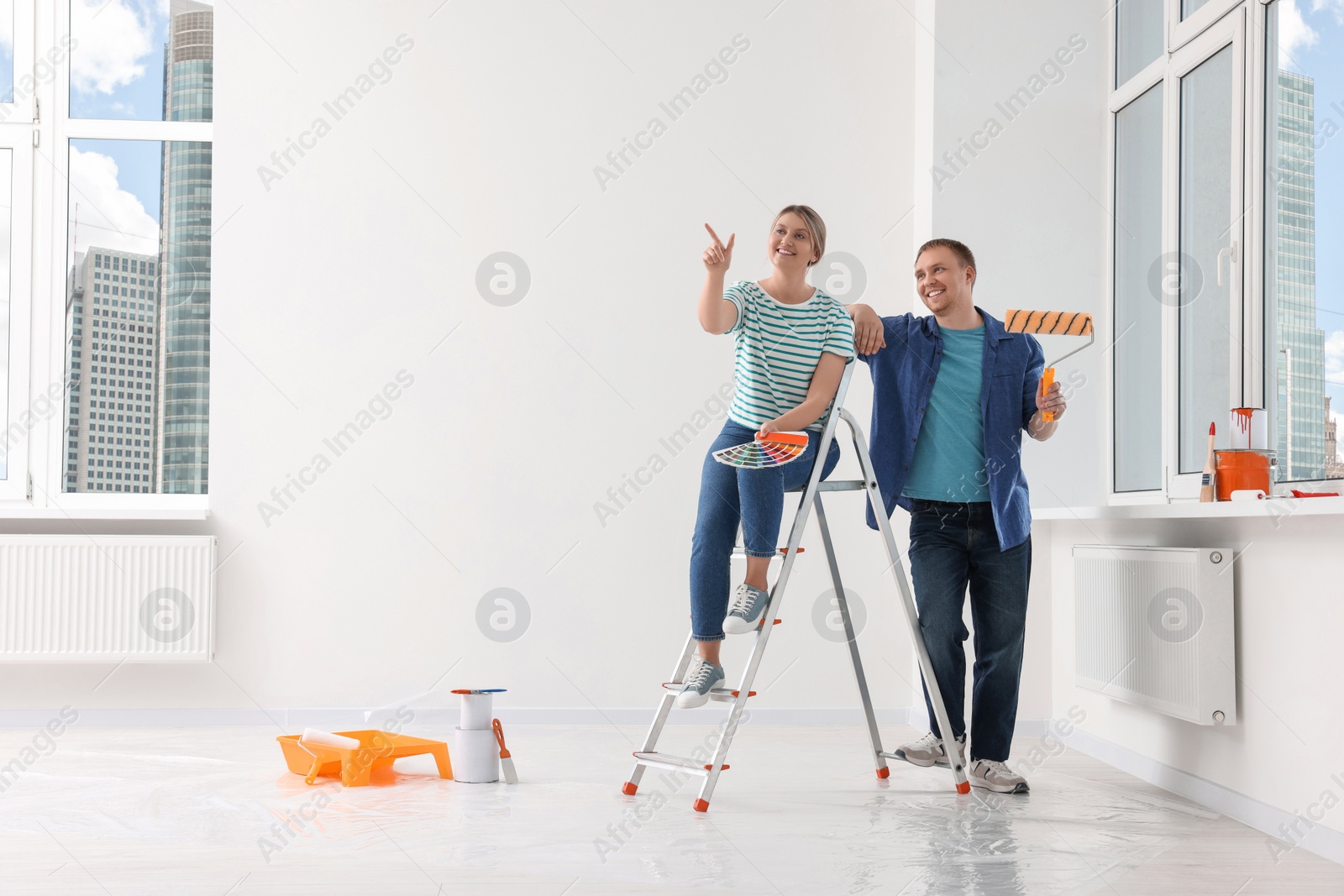 Photo of Happy couple discussing interior details in apartment during repair