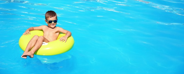 Little boy on inflatable ring in swimming pool, space for text. Banner design