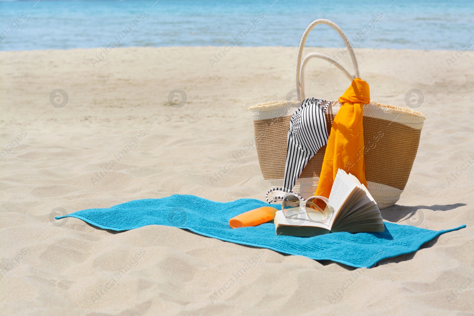 Photo of Blue towel, bag and beach accessories on sand, space for text