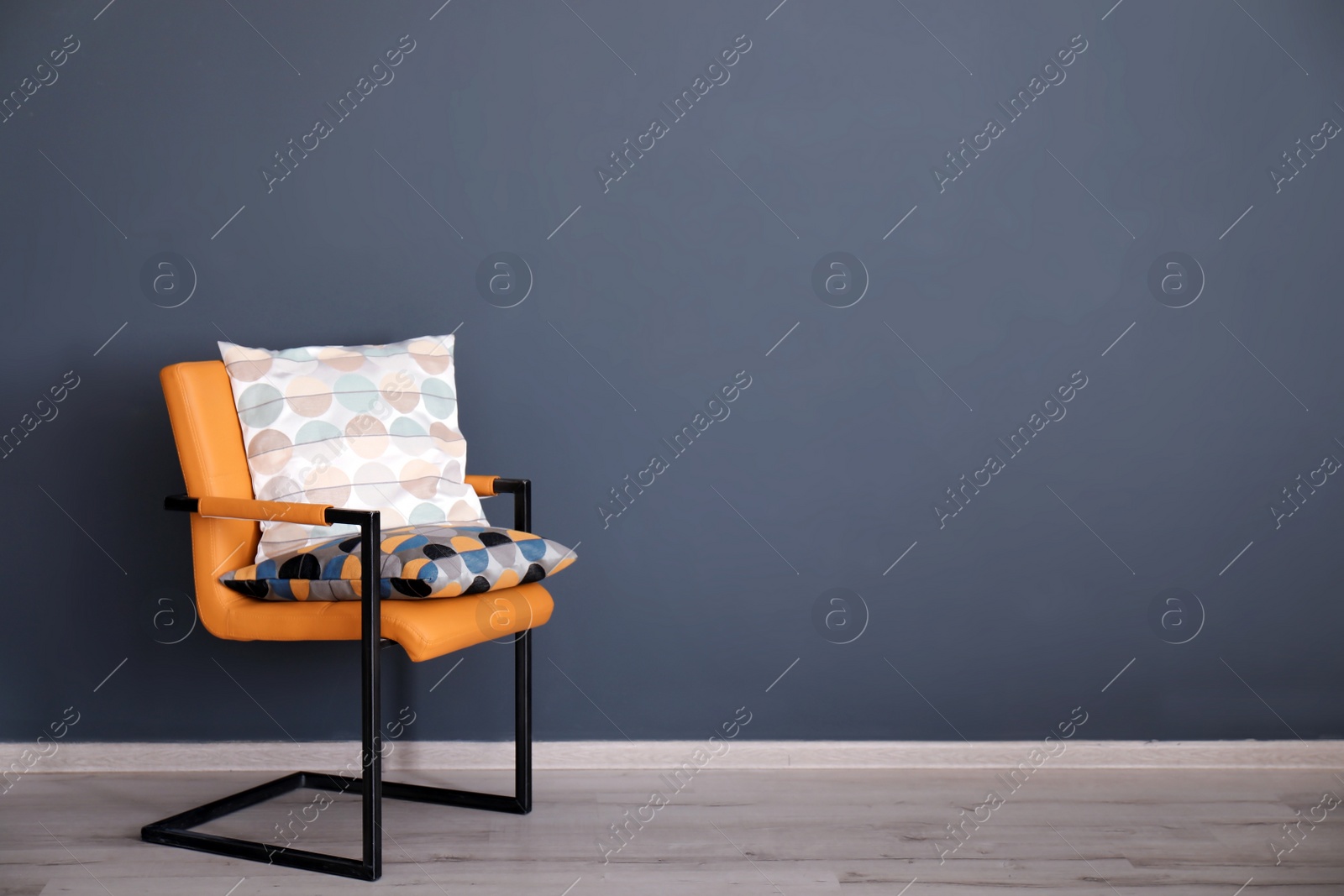 Photo of Soft pillows on armchair near grey wall