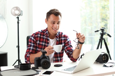 Photo of Portrait of photo blogger with cup of coffee and laptop at home. Online broadcast