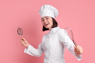 Happy confectioner with sieve and whisk on pink background
