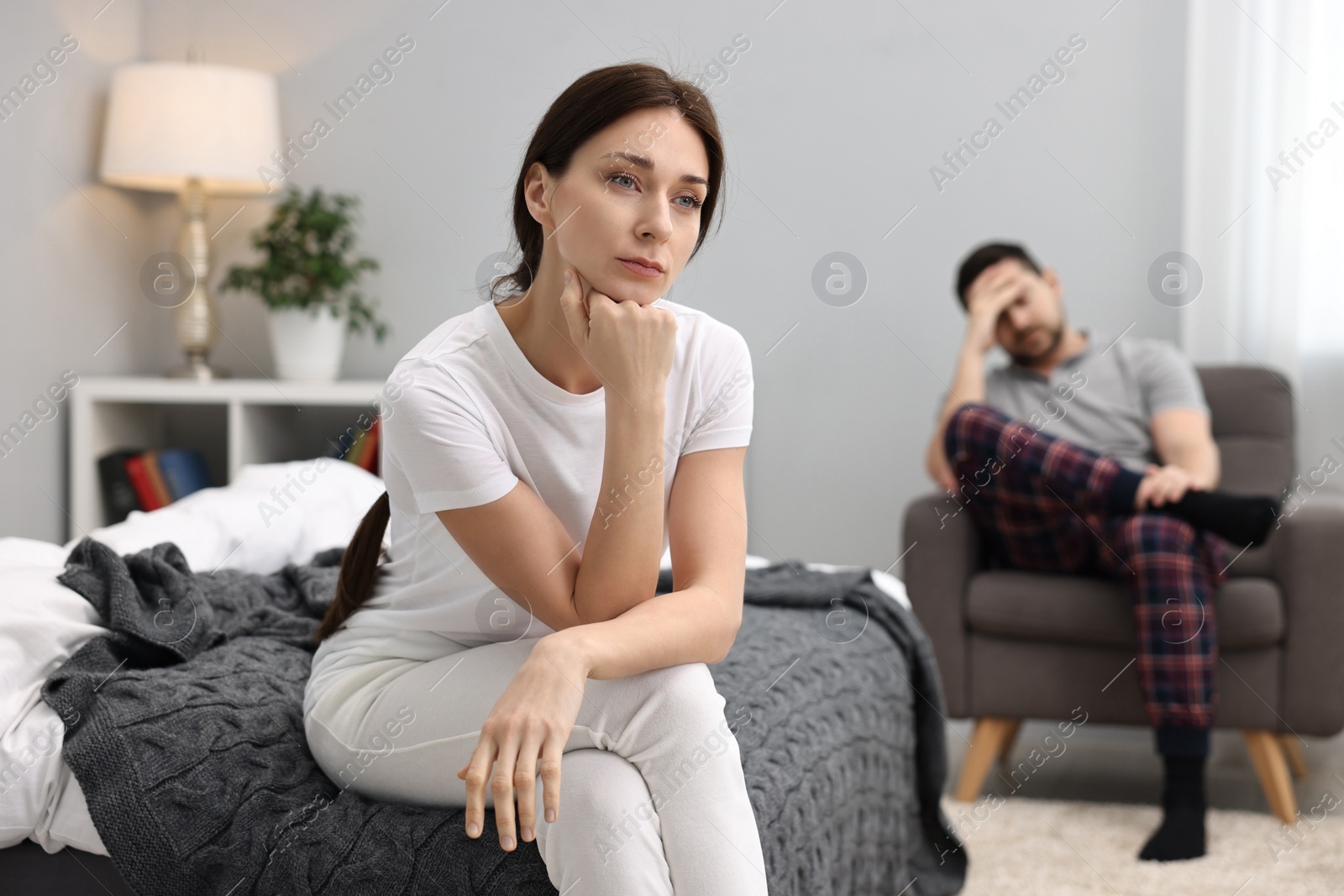 Photo of Offended couple ignoring each other after quarrel in bedroom, selective focus. Relationship problems