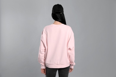 Young woman in sweater on grey background. Mock up for design