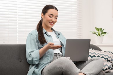 Woman having video chat via laptop on couch at home