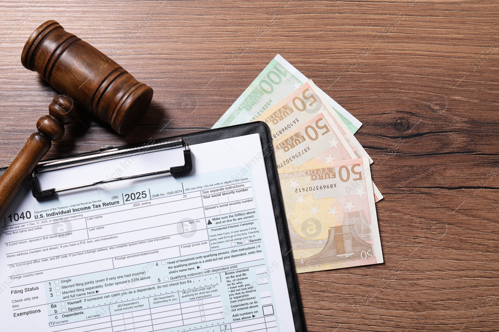 Photo of Tax return form, euro banknotes and gavel on wooden table, top view