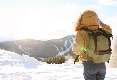 Woman with backpack enjoying mountain view during winter vacation. Space for text