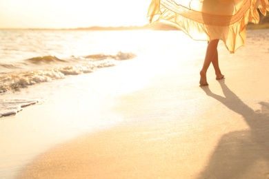 Photo of Young  woman walking on beach at sunset, closeup