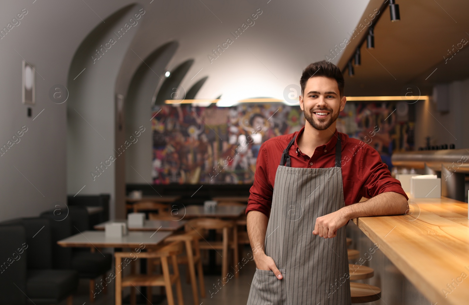 Photo of Young male business owner standing near counter in his cafe. Space for text